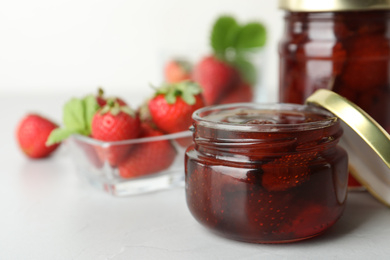 Photo of Delicious pickled strawberry jam and fresh berries on light table. Space for text