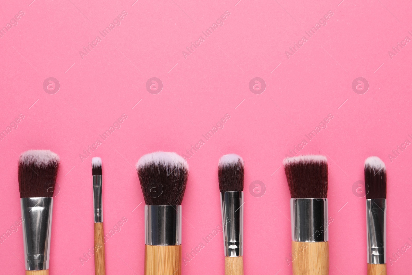 Photo of Set of makeup brushes on pink background, flat lay. Space for text