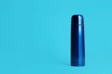 Photo of Stylish thermo bottle on light blue background, space for text