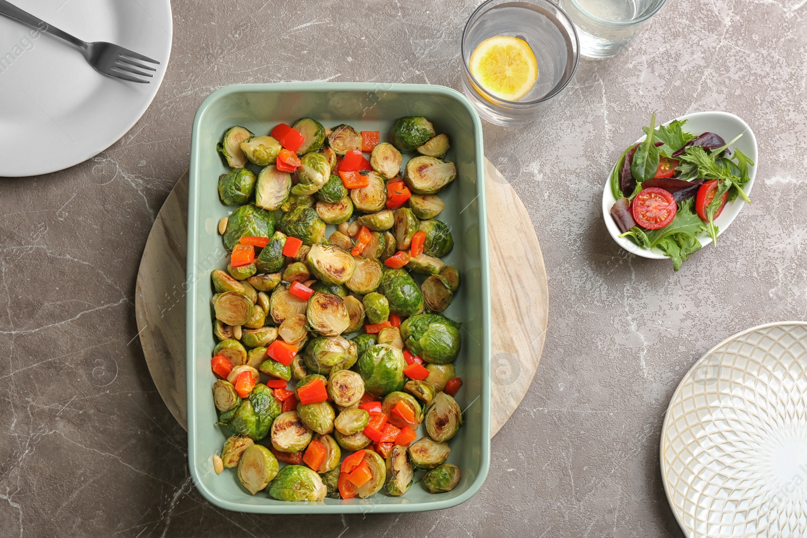 Photo of Delicious roasted brussels sprouts with bell pepper and peanuts served on marble table, flat lay