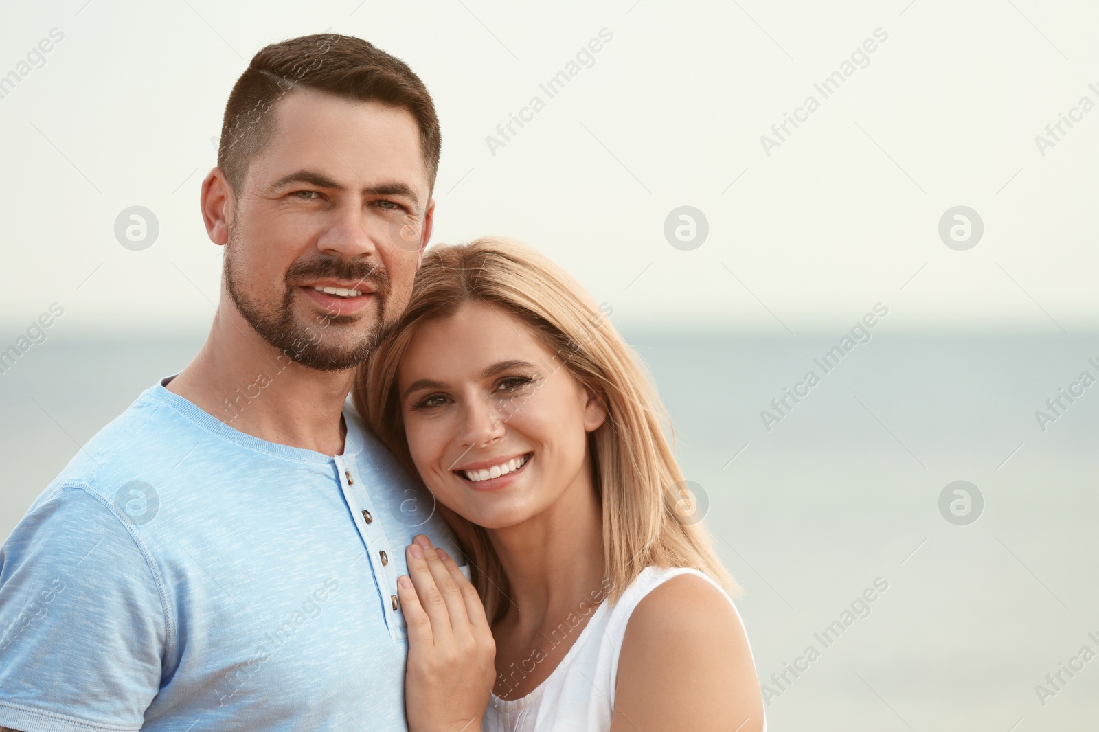 Photo of Happy romantic couple spending time together on beach, space for text