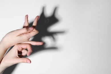 Shadow puppet. Woman making hand gesture like rabbit on light background, closeup. Space for text