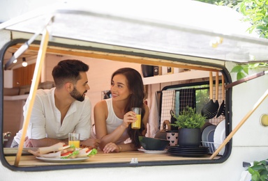 Photo of Happy young couple having breakfast in trailer. Camping vacation