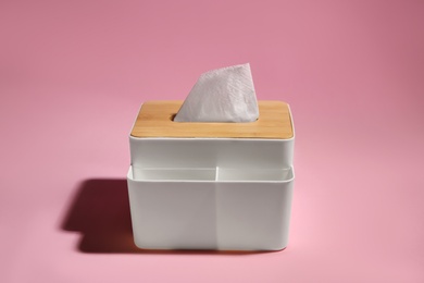 Photo of Holder with paper tissues on pink background