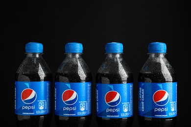 MYKOLAIV, UKRAINE - FEBRUARY 08, 2021: Plastic bottles of Pepsi with water drops on black background, closeup