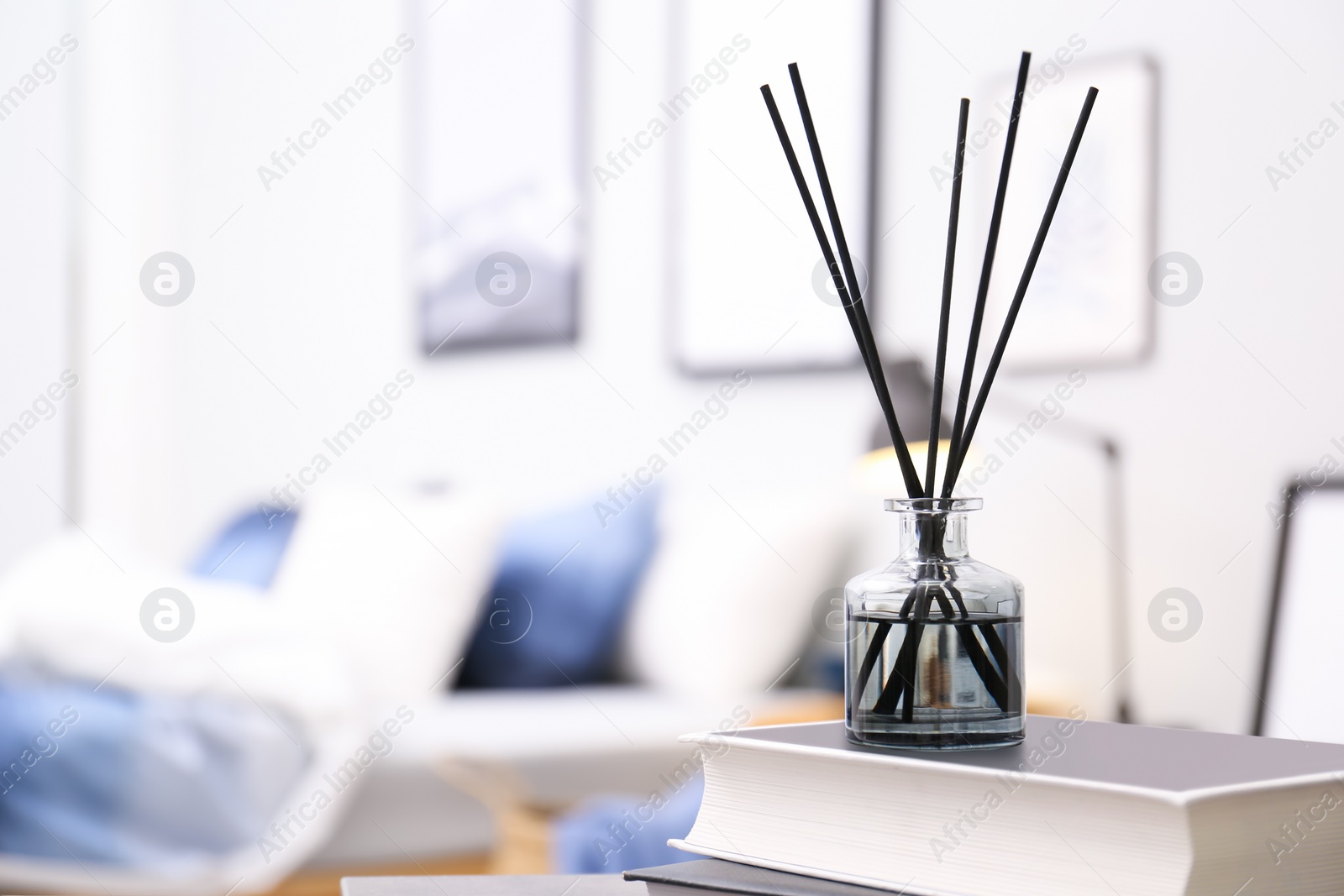 Photo of Aromatic reed air freshener and books on table in room. Space for text