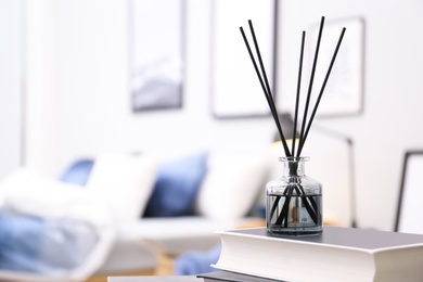 Aromatic reed air freshener and books on table in room. Space for text