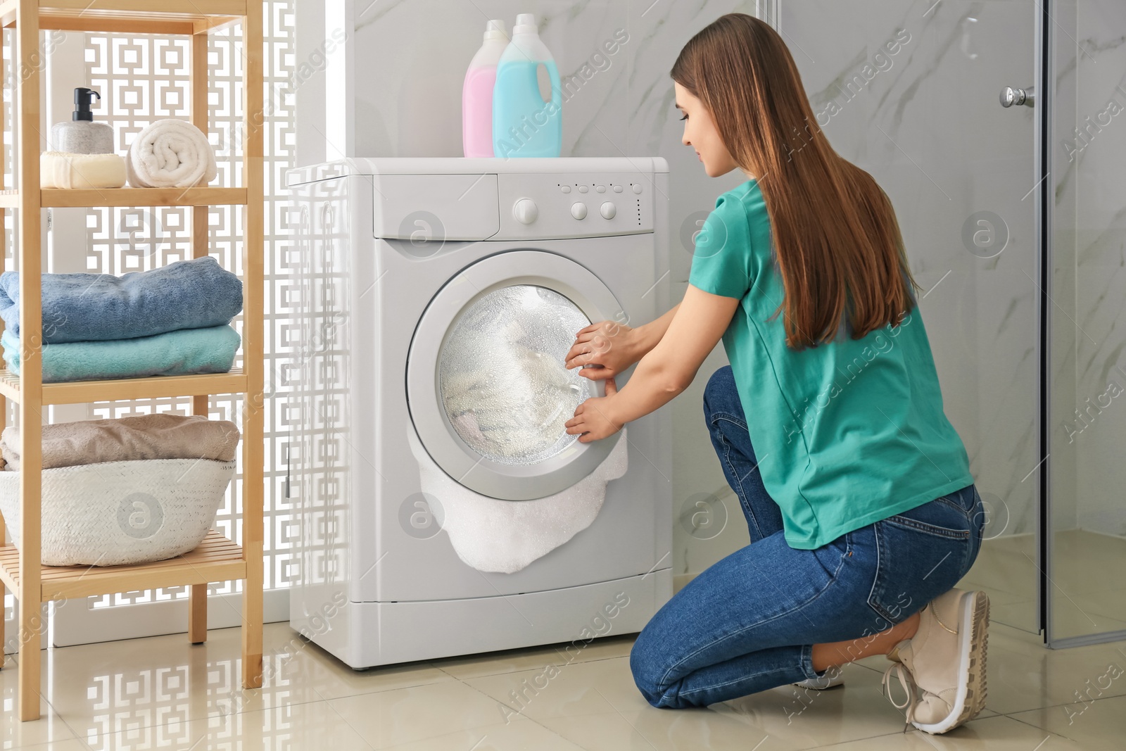 Image of Woman near broken washing machine in room. Foam coming out from drum during laundering