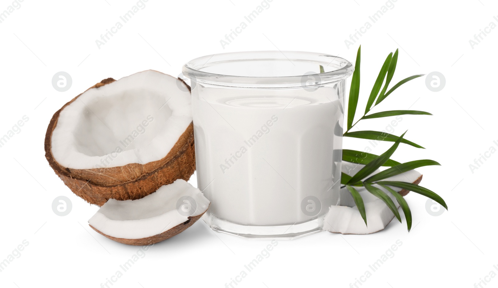 Photo of Glass of delicious vegan milk, coconut pieces and green leaves on white background