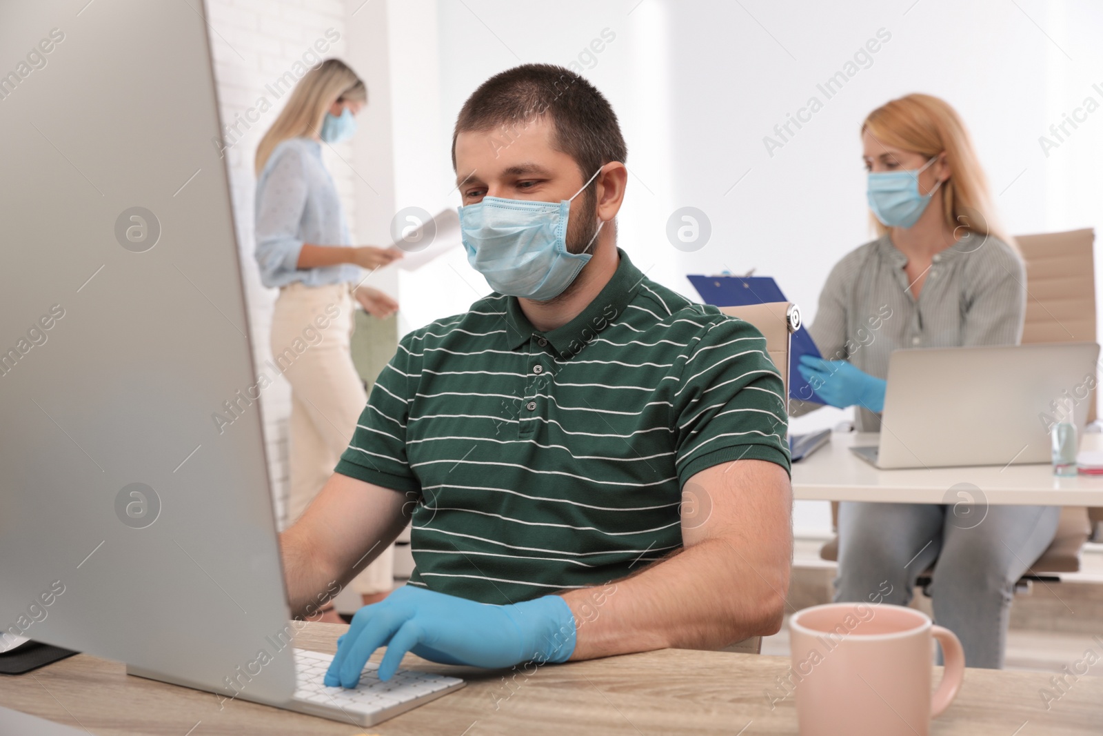 Photo of Office employees in respiratory masks at workplace