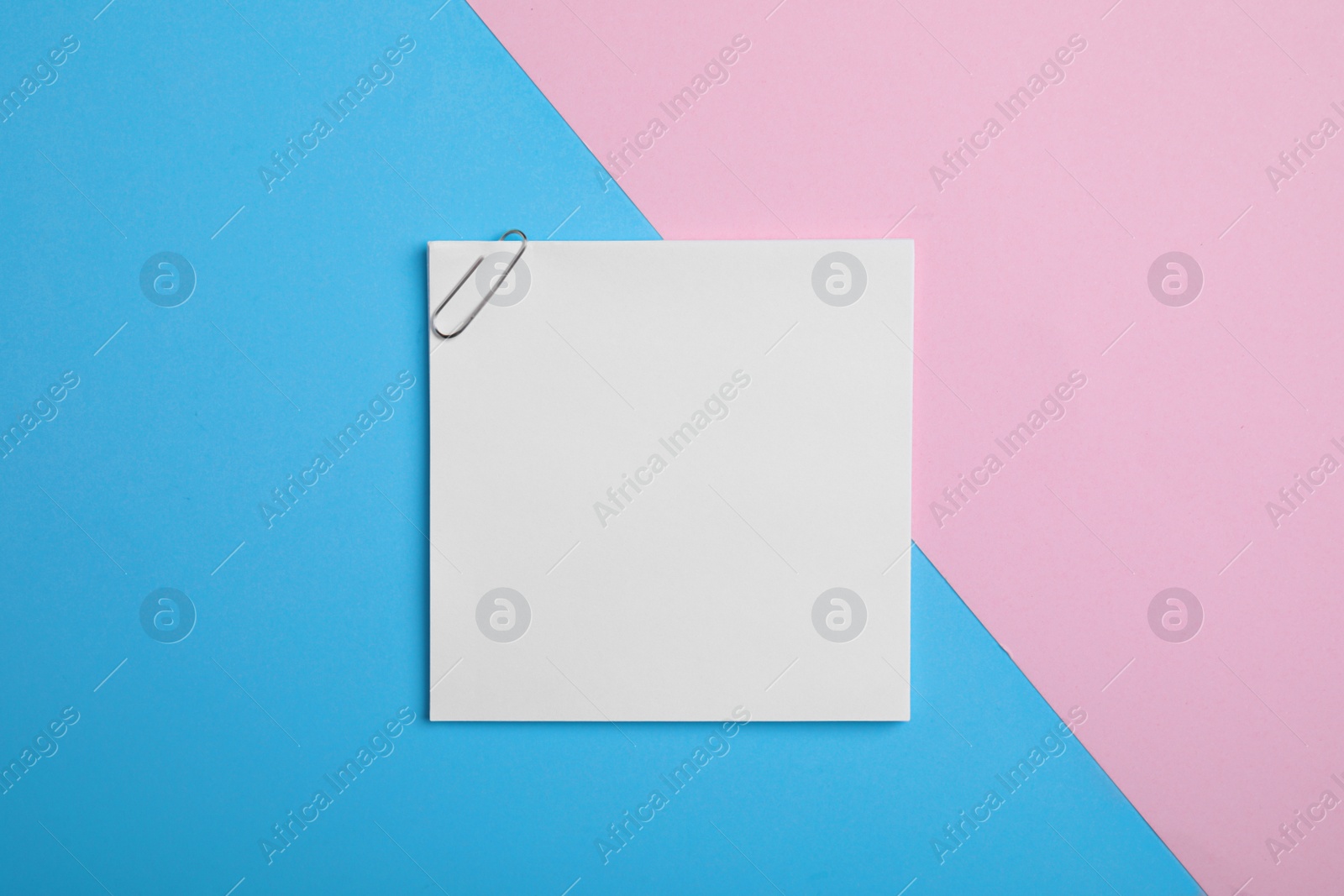 Photo of Sheet of paper with clip on color background, top view