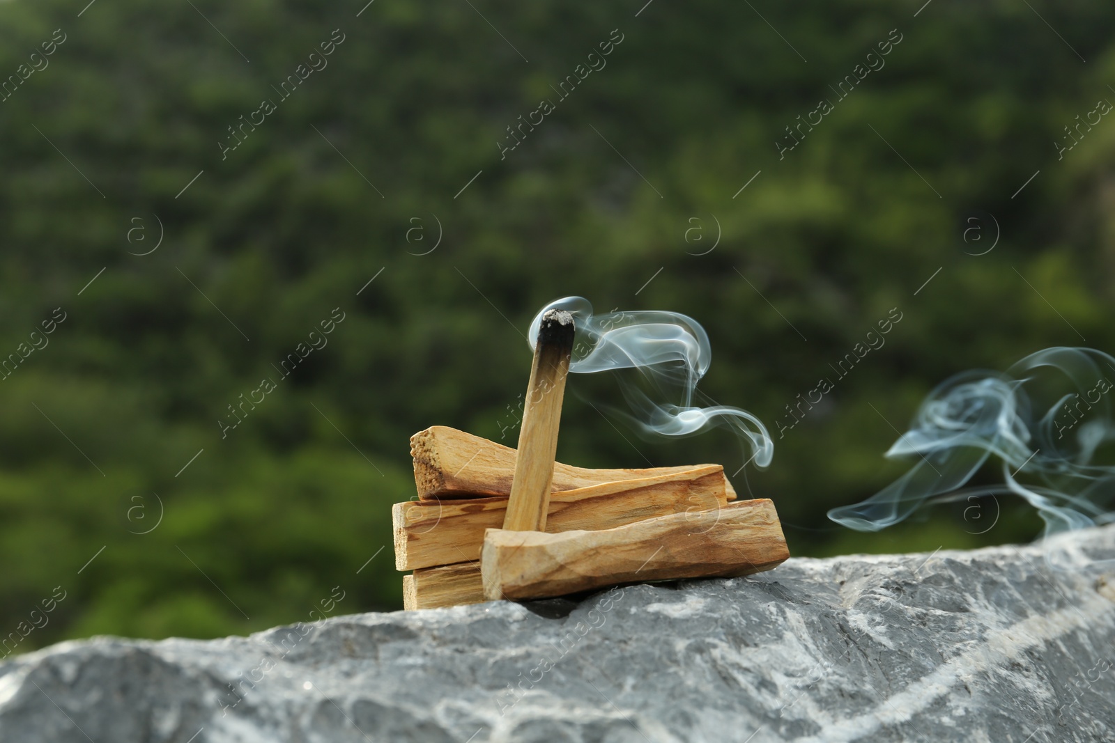 Photo of Burning palo santo stick on stone surface outdoors