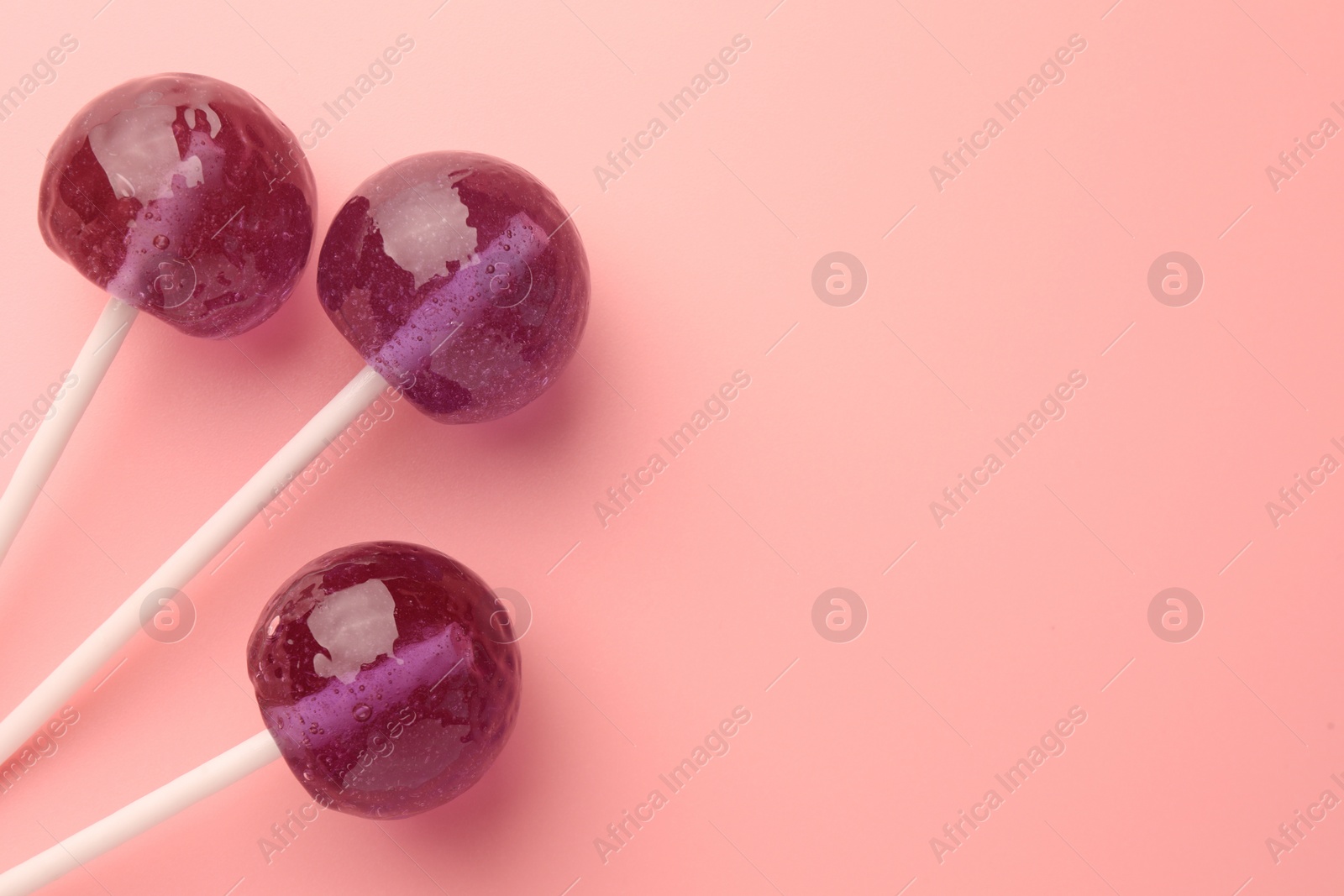 Photo of Tasty lollipops on pink background, flat lay. Space for text