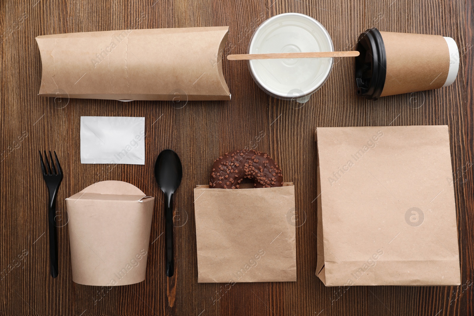 Photo of Flat lay composition with paper bags and different takeaway items on wooden background. Space for design