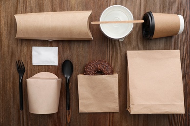 Flat lay composition with paper bags and different takeaway items on wooden background. Space for design