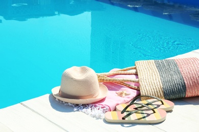 Photo of Beach accessories on wooden deck near swimming pool. Space for text