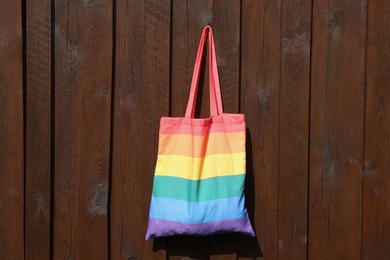 Photo of Rainbow bag hanging on wooden background, space for text. LGBT pride