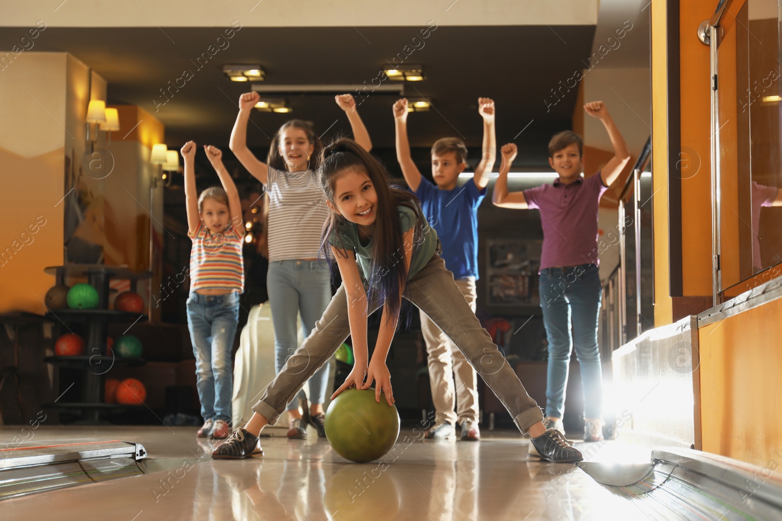 Photo of Girl throwing ball and spending time with friends in bowling club