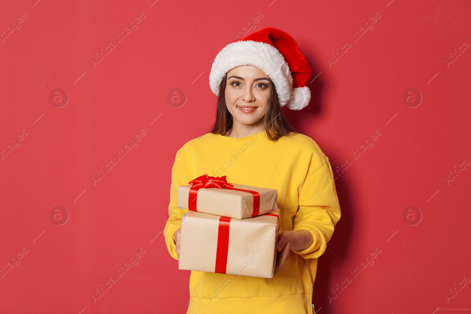 Photo of Young woman with Christmas gifts on color background