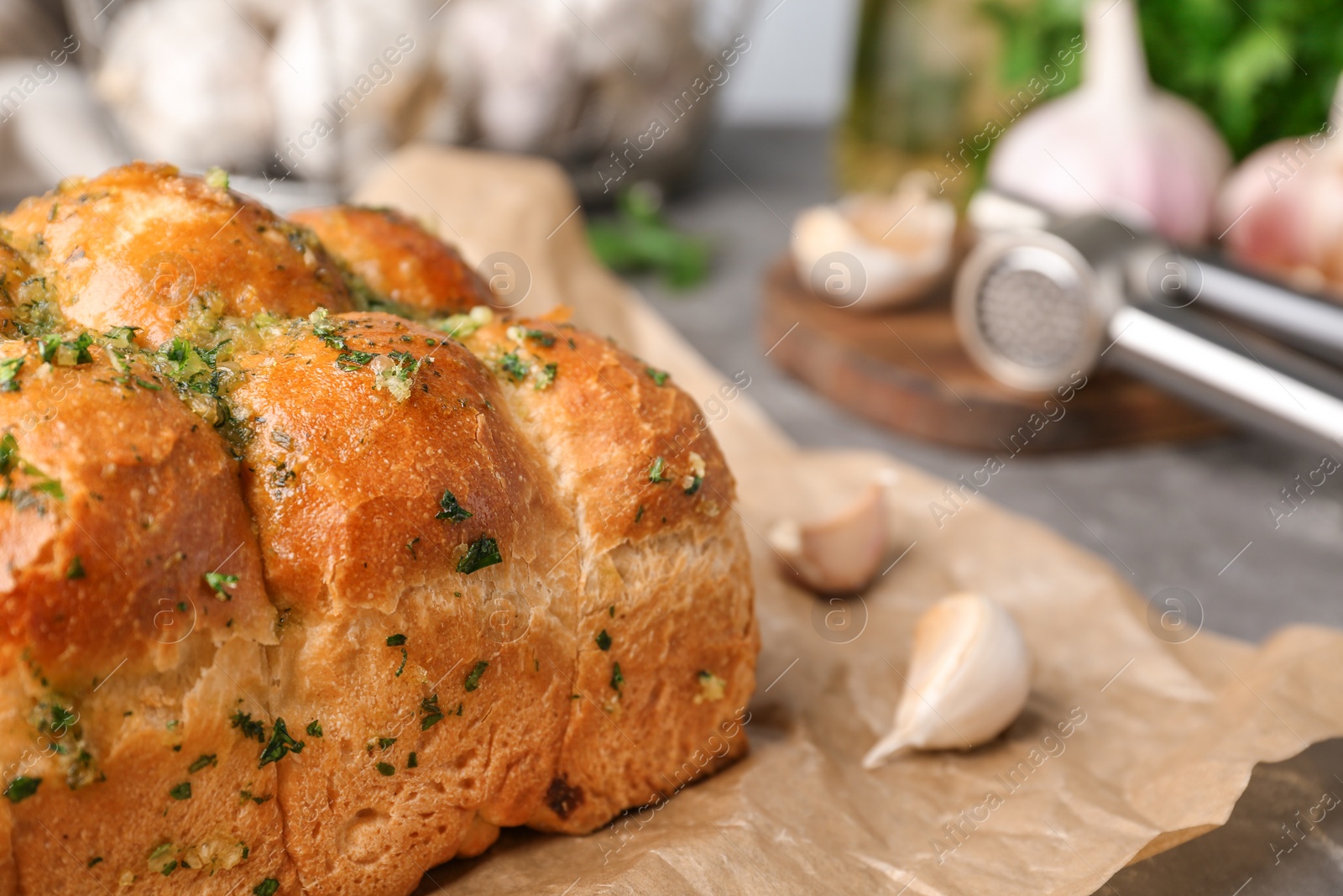 Photo of Buns of bread with garlic and herbs on grey table, closeup