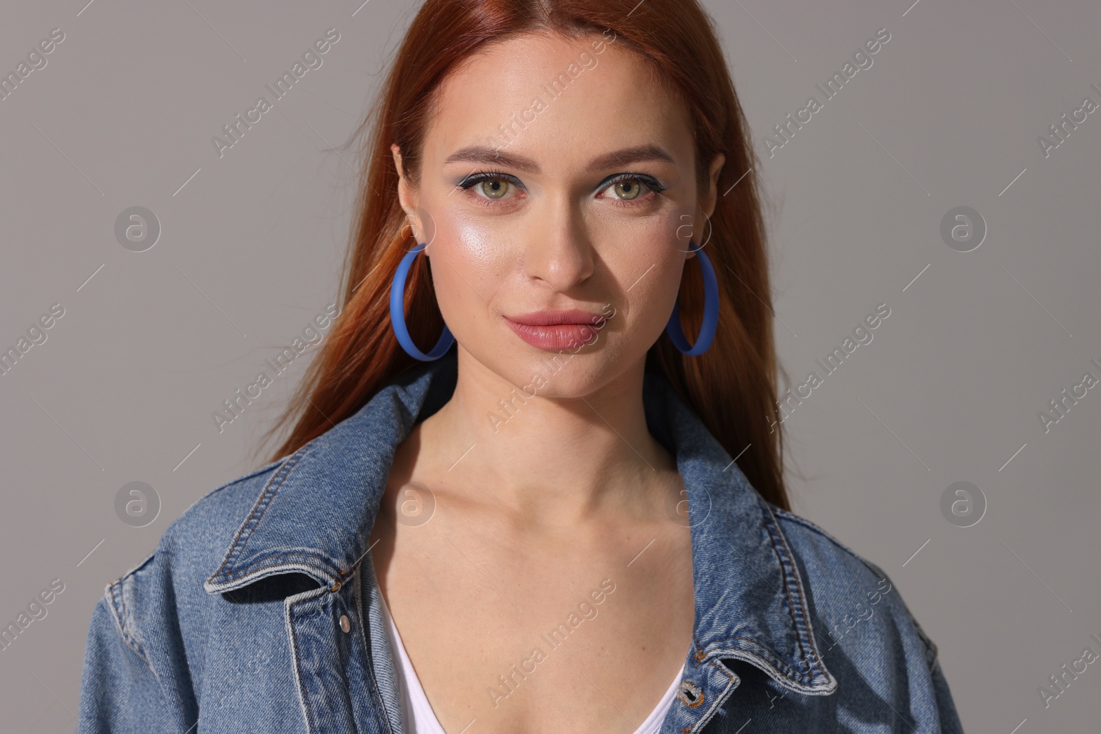 Photo of Beautiful young woman in denim jacket on gray background