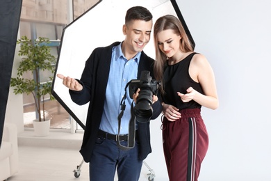 Photo of Photographer showing model her photos in professional studio