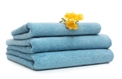 Stack of clean folded towels with flowers on white background