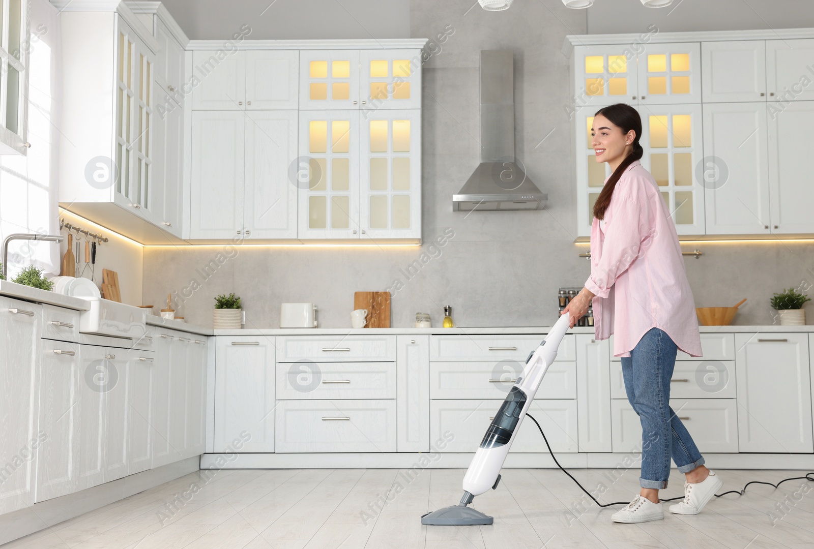 Photo of Happy woman cleaning floor with steam mop in kitchen at home. Space for text