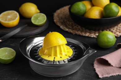 Photo of Squeezer, fresh lemons and limes on black table