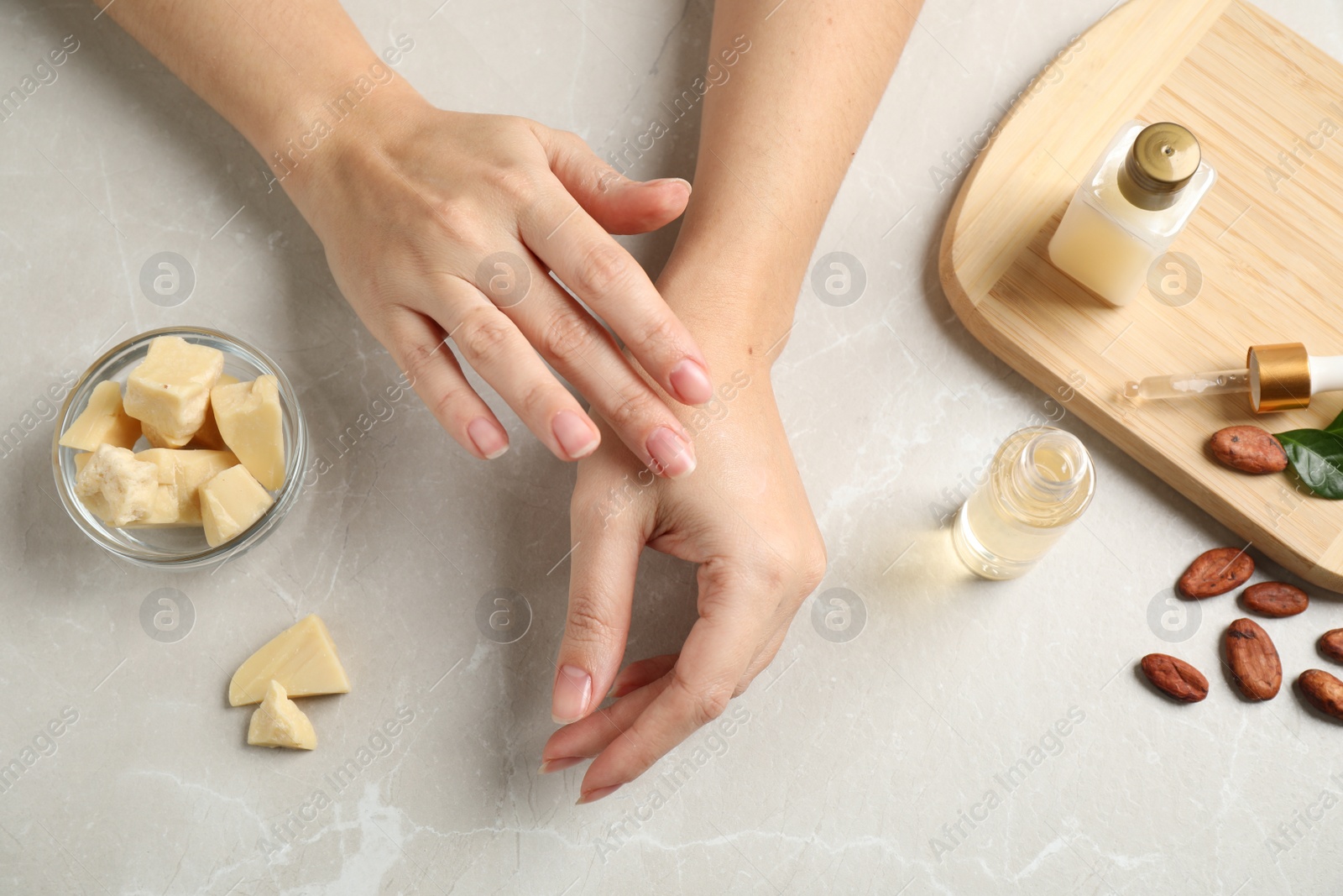 Photo of Woman applying organic cocoa butter at table, top view