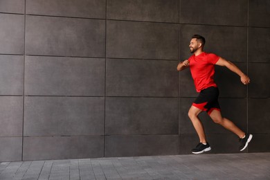 Photo of Happy man running near building outdoors. Space for text