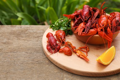 Delicious red boiled crayfish and orange on wooden table. Space for text
