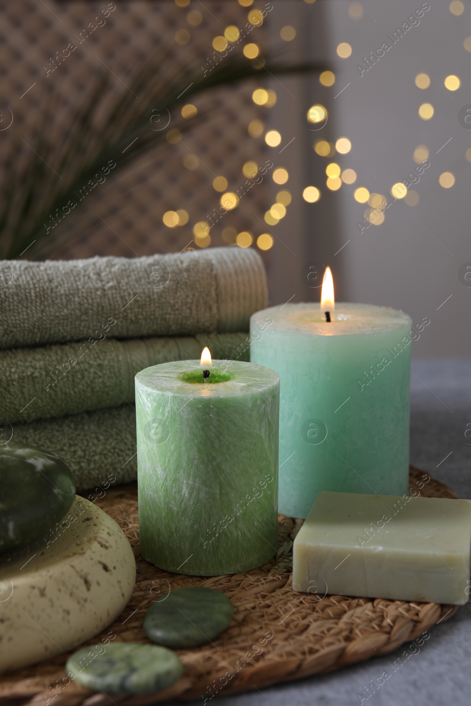 Photo of Spa composition. Burning candles, stones, soap and towels on grey table