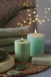 Photo of Spa composition. Burning candles, stones, soap and towels on grey table