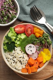 Photo of Bowl with many different vegetables and rice on wooden table, flat lay. Vegan diet