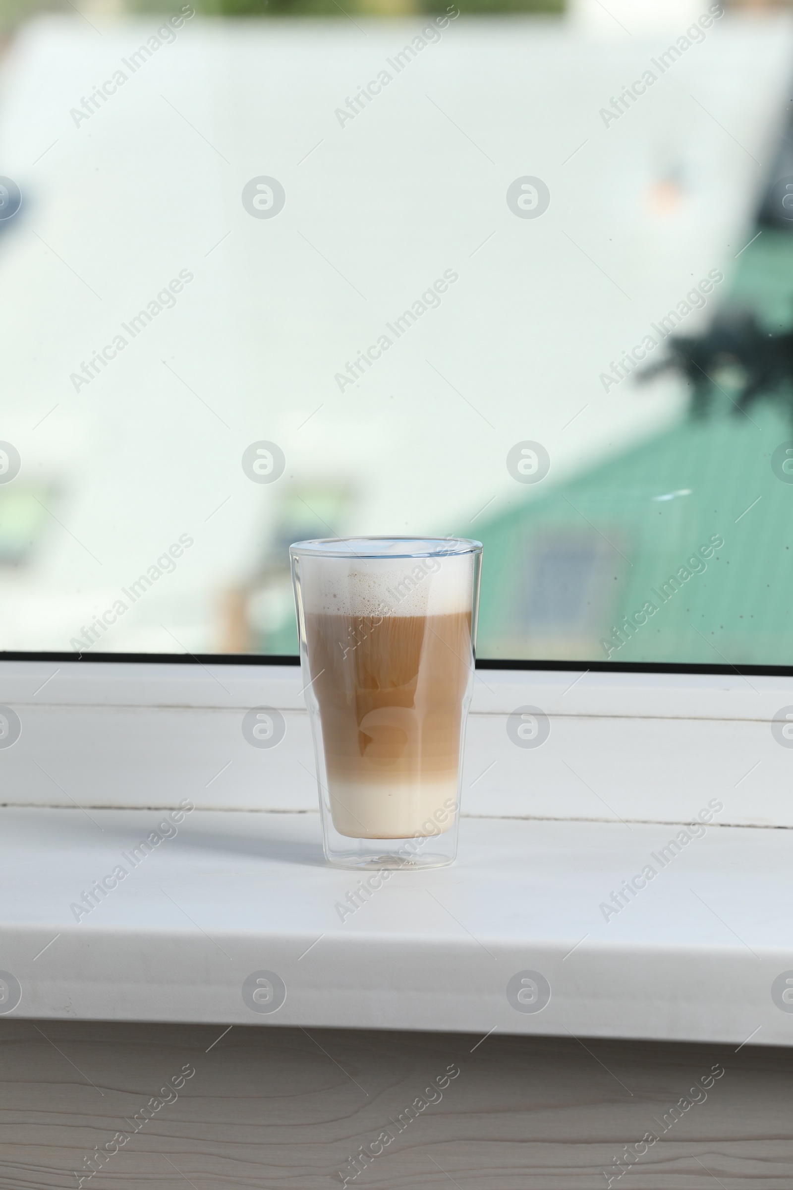 Photo of Glass with latte on white window sill