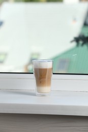 Glass with latte on white window sill