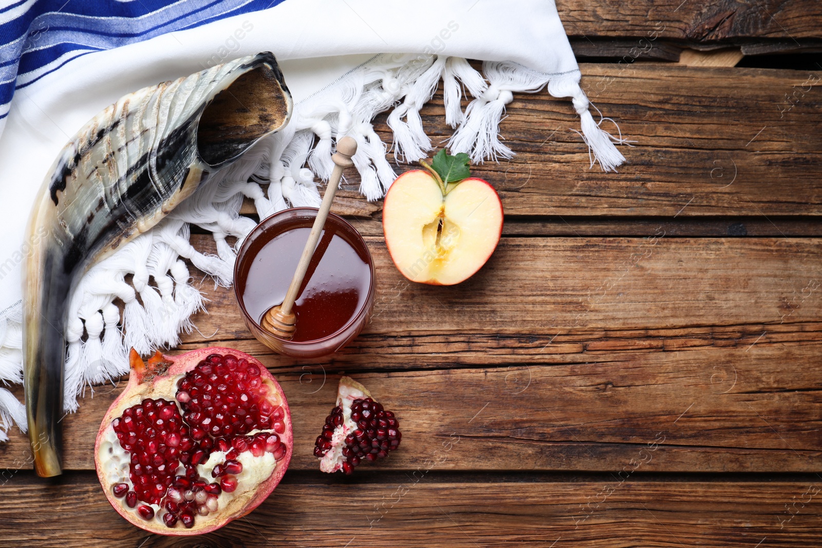 Photo of Honey, pomegranate, apples and shofar on wooden table, flat lay with space for text. Rosh Hashana holiday