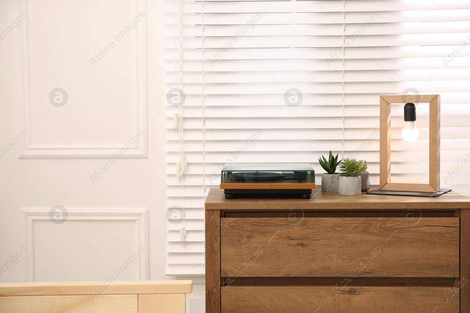 Photo of Stylish turntable with vinyl record on wooden chest of drawers indoors, space for text