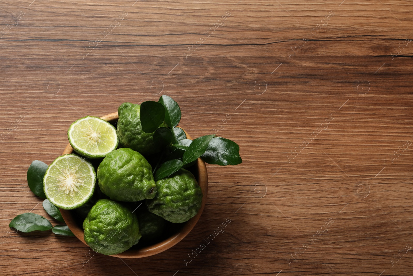 Photo of Fresh ripe bergamot fruits with green leaves on wooden table, top view. Space for text