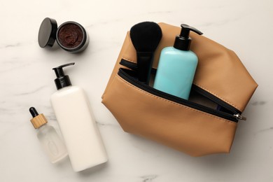 Preparation for spa. Compact toiletry bag and different cosmetic products on white table, flat lay
