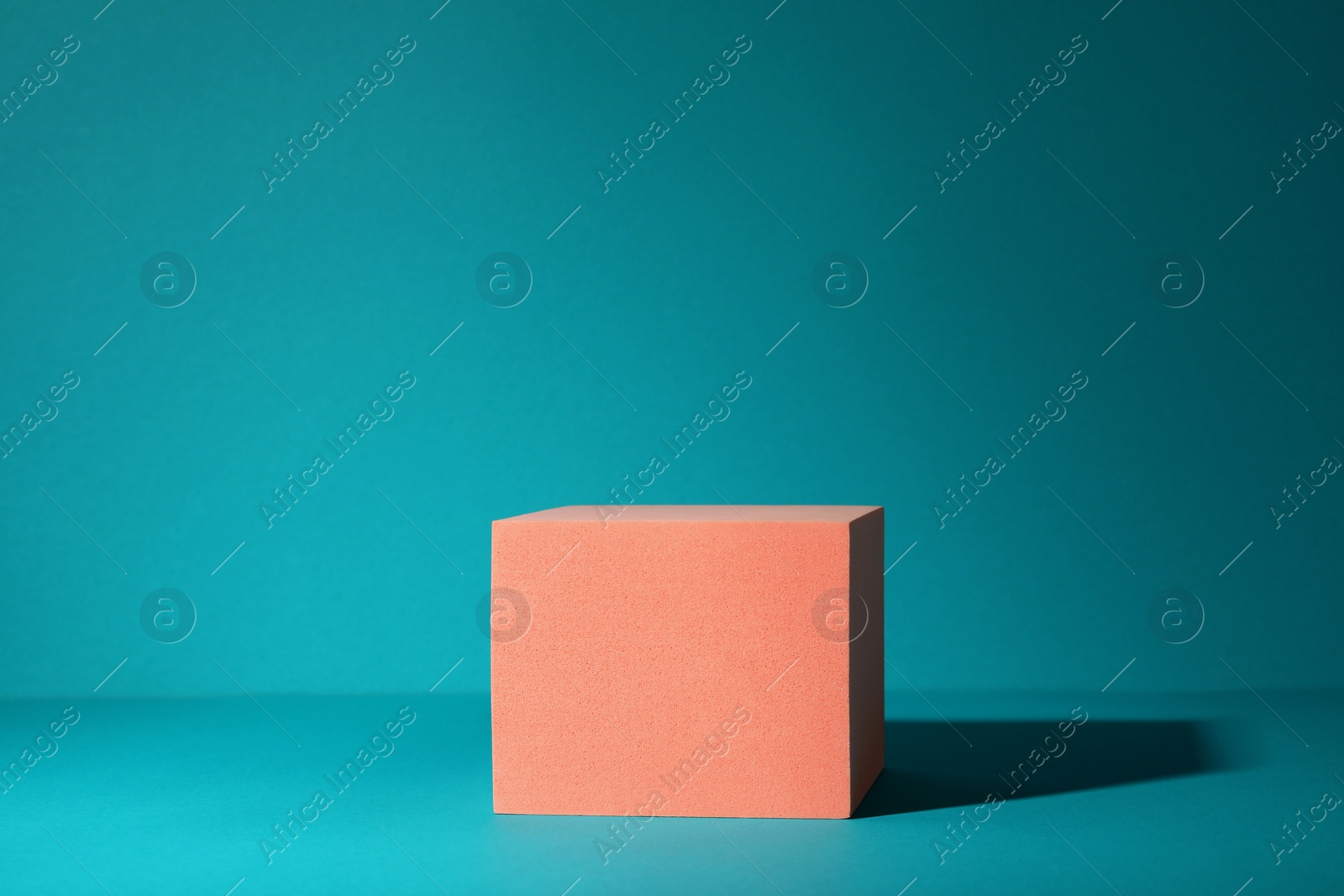 Photo of Orange geometric figure on teal background, space for text. Stylish presentation for product