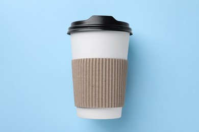 Photo of One paper cup on light blue background, top view. Coffee to go