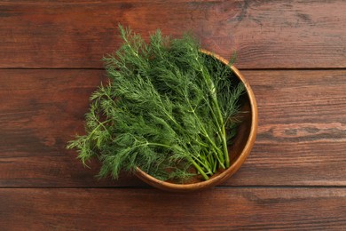 Photo of Bowl of fresh green dill on wooden table, top view