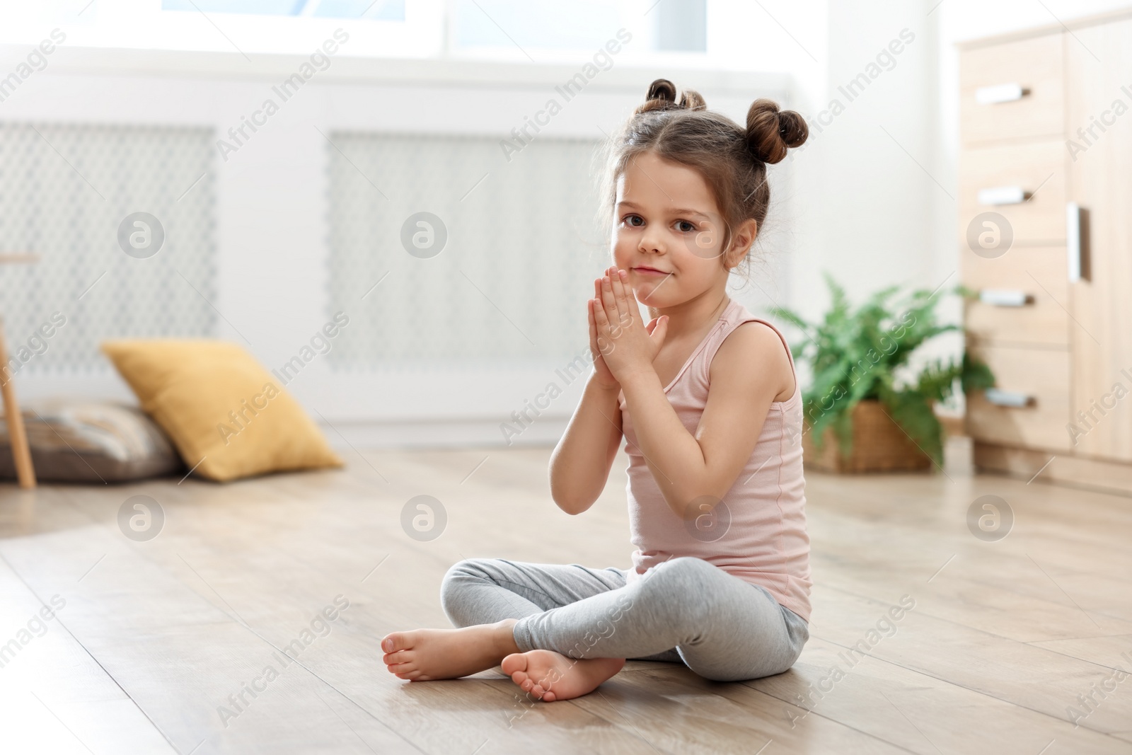 Photo of Little cute girl practicing yoga on floor at home