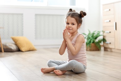 Little cute girl practicing yoga on floor at home