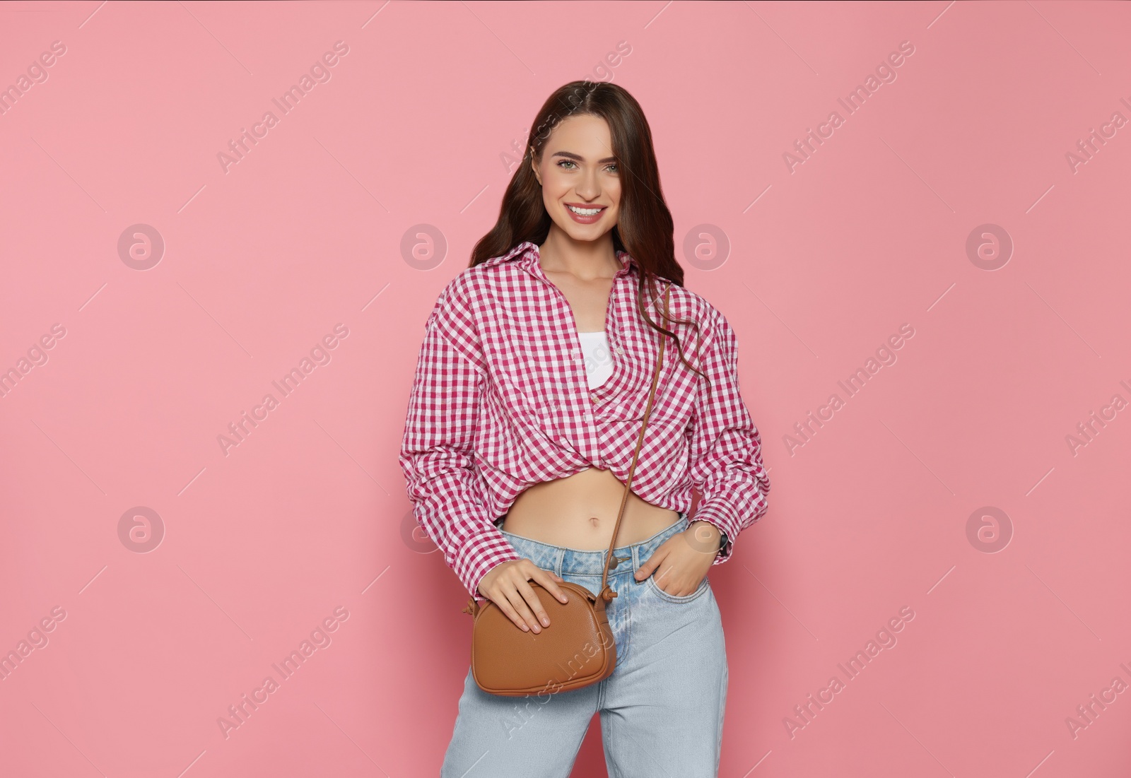 Photo of Beautiful young woman in fashionable outfit with stylish bag on pink background