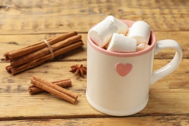 Photo of Tasty hot chocolate with marshmallows and spices on wooden table, closeup