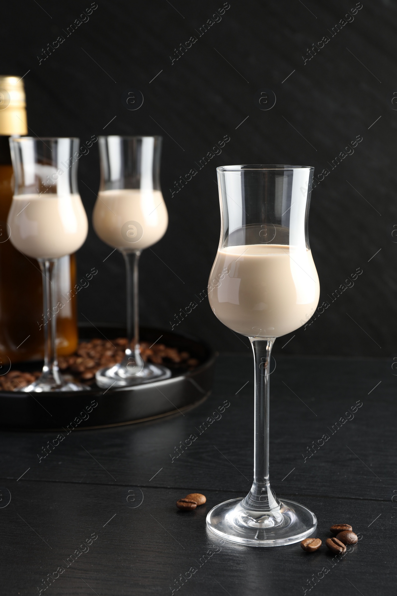 Photo of Coffee cream liqueur in glasses and beans on black wooden table