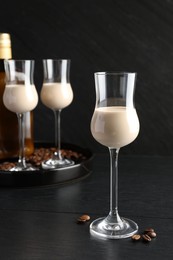 Coffee cream liqueur in glasses and beans on black wooden table